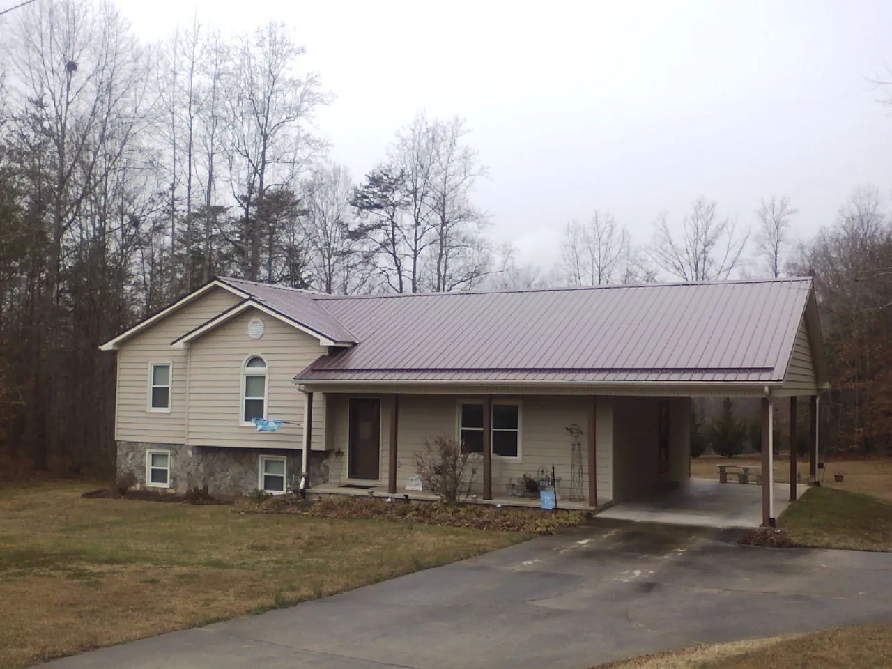 Burgundy metal roof on a tan split level home with an attached carport in Trout Creek