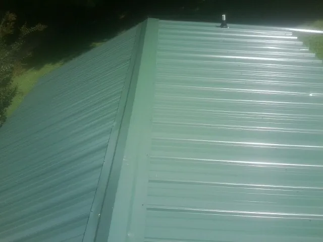 New green metal panels meeting at the ridge of a roof — Flat Roof Repair work by our crew in Trout Creek