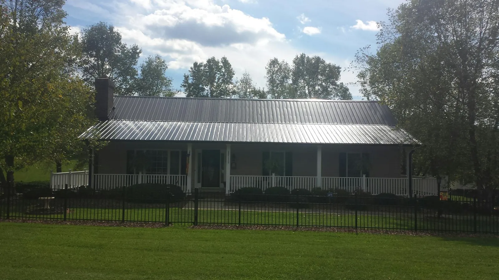 Gray metal roof on a brick ranch with a full width front porch — Gutter Guard Installation work by our crew in Trout Creek